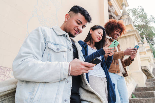 istock Multiracial group of three young friends enjoying and smiling using their mobile phone app. Diverse teenagers having fun sharing messages with each other on cellphone. Communication concept 1526426058