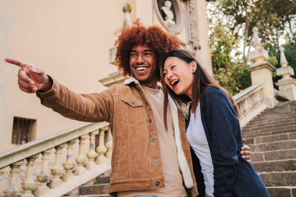 istock Young multiracial couple walking and having fun on a romantic trip pointing monument. African american boyfriend and chinese girlfriend smiling bonding together sightseeing with affectionate attitude 1526433761