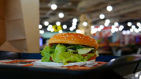 A beautiful fresh hamburger with lots of lettuce in it on the salver in a fast food restaurant close-up