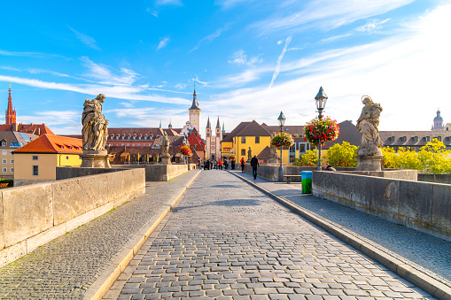 Old Main bridge with statues of holy figures and the the towers Grafeneckart and St. Kiliansdom, in the Bavarian city of Würzburg, Germany. stock photo