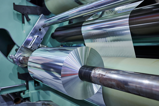 Side view of aluminum thin & foil roll at automated manufacturing equipment.