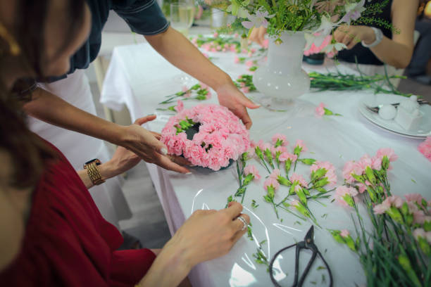 アジア人女性がフラワーアレンジメントのクラスを受講し、たくさんのカーネーションを使ってハート型の花束を作り、母の日を祝うために母親に贈っています。 - carnation mothers day florist flower ストックフォトと画像