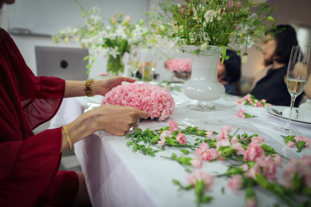 アジア人女性がフラワーアレンジメントのクラスを受講し、たくさんのカーネーションを使ってハート型の花束を作り、母の日を祝うために母親に贈っています。 - carnation mothers day florist flower ストックフォトと画像