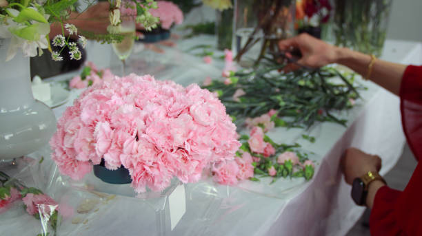 アジア人女性がフラワーアレンジメントのクラスを受講し、たくさんのカーネーションを使ってハート型の花束を作り、母の日を祝うために母親に贈っています。 - carnation mothers day florist flower ストックフォトと画像