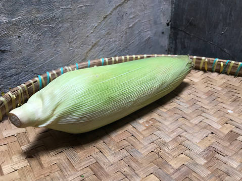 Green corn on a woven bamboo. Prepared for cooking.