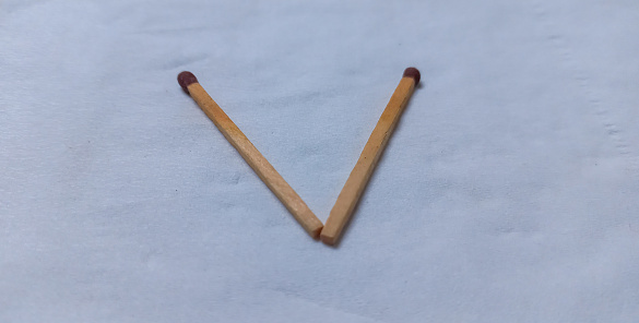 Two matchsticks form the letter v on white background.