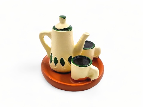 Miniature teapot and cup on white background