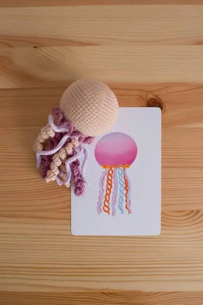 Photo of Handmade crocheted card for baby on wooden background.