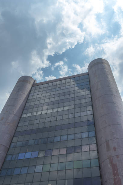 istock Old office commercial building with transparant windows and rounded pillar in sunny cloudy blue sky afternoon 1527123378