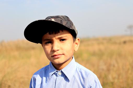 Elementary age child of Indian ethnicity standing portrait outdoor in nature during summer season.