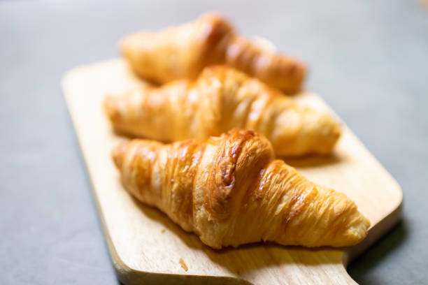 istock Fresh croissant on wooden board with nature sunlight through window. 1527421235
