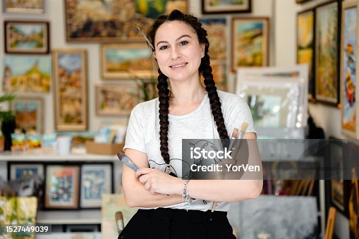 istock Portrait of a Talented Young Female Artist With Arms Crossed Holding Brushes in her Creative Art Studio 1527449039