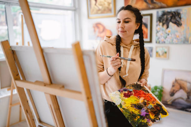 istock Young talented female painter enjoying while painting in art studio 1527449548