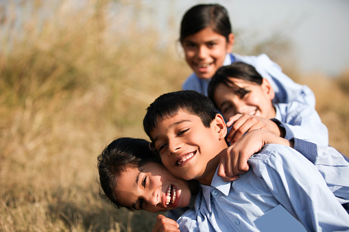 Elementary age playful children of Indian ethnicity standing/ Playing portrait together outdoor in nature during springtime.