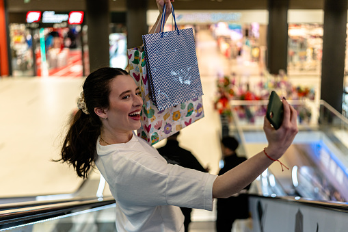 A young woman is walking through the shopping mall, finding solace in retail therapy and browsing her favorite stores for new clothing and accessories