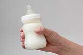 Isolated bottle feeding full of milk in woman hand on white background
