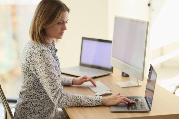 istock A woman sits at a table with laptops, a close-up 1527571575