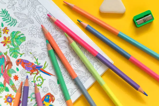 Adult coloring book and pastel two sidde pencils on a yellow background. Anti stress coloring book.