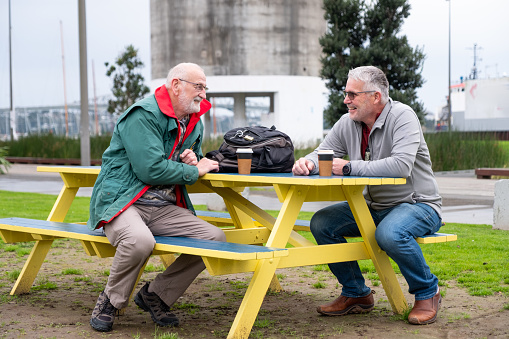 Mature males having a good catch up over coffee in the park