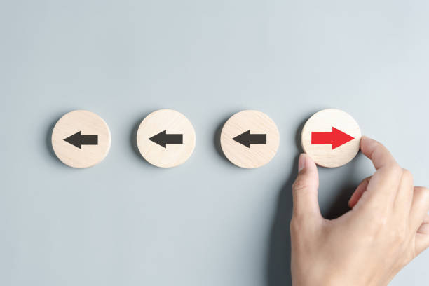 istock Hand holding wood block Red arrow and different direction facing opposite direction with black arrow for business disruption and technology transformation and different thinking idea concept. 1527651290