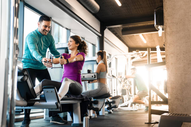 istock Dedicated man coach showing right exercise technique to young female newcomer 1527653368