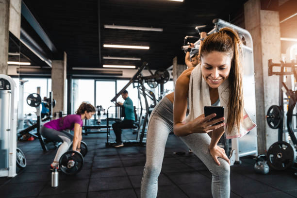 istock Happy athletic woman using phone while taking a break from exercising in the gym 1527653883