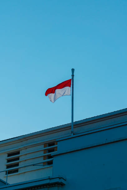 Indonesian flag above the building Indonesian flag fluttering above white retro building jakarta slums stock pictures, royalty-free photos & images