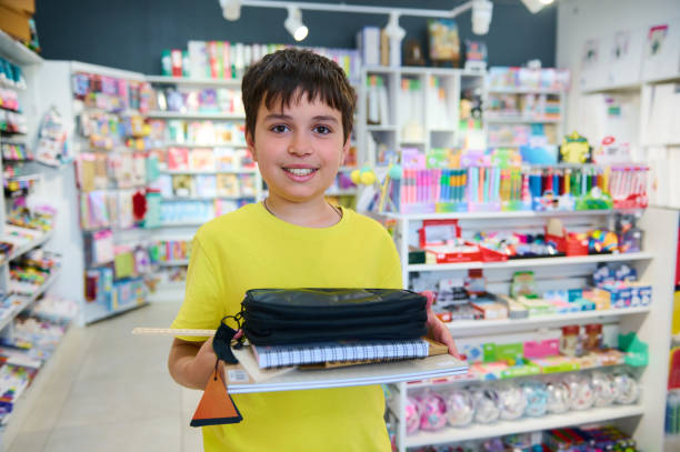 Diligent teenage schoolboy collecting school supplies from stationery store, smiling looking at camera. Back to school stock photo