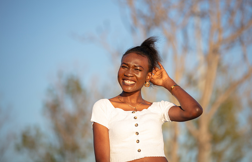 Young black girl is smiling on the outside at sunset.