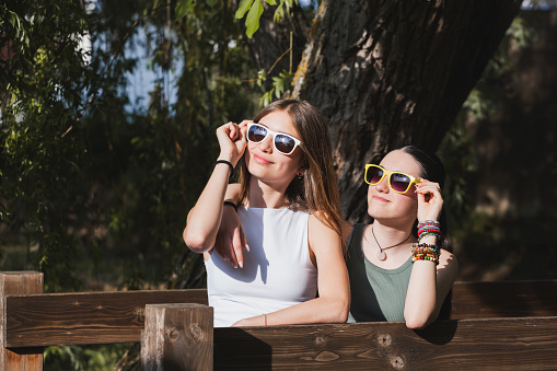 Two beautiful happy girls in sunglasses spend summer vibes in nature background. Young active people concept.