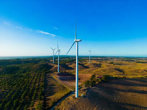 Wind turbine generating electricity, windmills against the background of a green field, an alternative source of energy, view from a drone