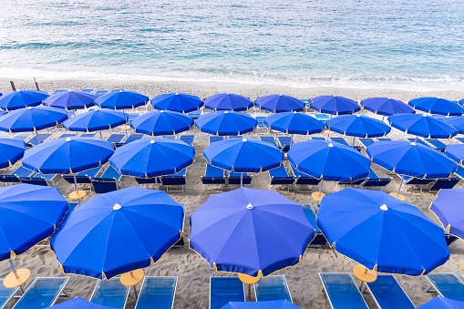 Colorful umbrellas and chairs along the beach front of Monterosso coast greeting tourist, one of the village in Cinque Terre, Italy