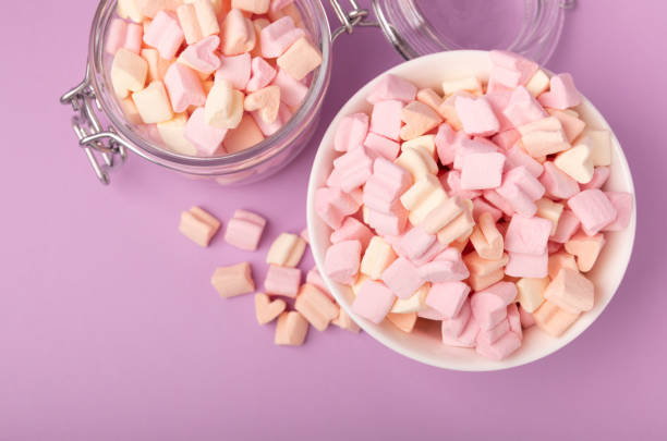 istock Marshmallows on a lilac background in a glass bowl. White marshmallow flat lay. Sweets and snacks for a snack. Chewing candies close-up. Copy space. Place for text. Winter food concept. 1527823313