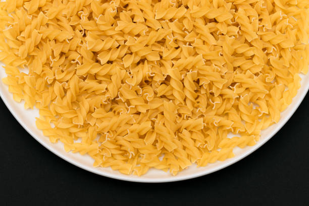 istock Uncooked Fusilli Pasta on White Plate 1527873930