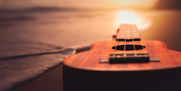 Ukulele on beach at sunset