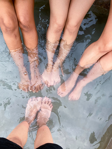A vertical grayscale closeup of the woman's feet above the water surface.