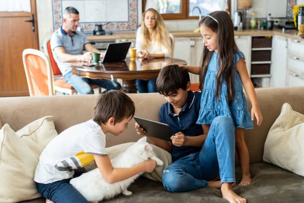 istock Three kids with a gadget on a couch at home 1527900199
