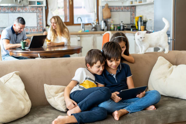 istock Brothers looking at a device screen, with sister and cat behind 1527900206