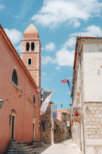 Bell tower of the Church of St. Justine and narrow street of old town of Rab on the island Rab, Croatia.