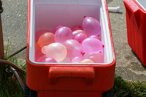 A red cooler with colorful water balloons inside.