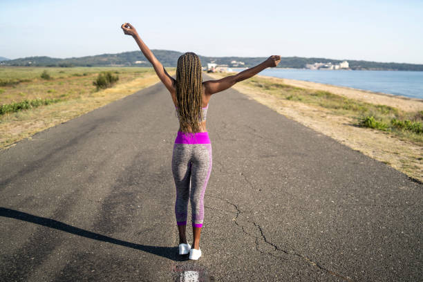 istock Woman with arms outstretch walking along an empty road 1527909311