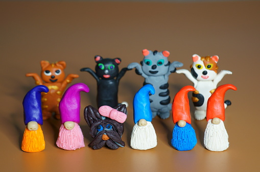Figurines of colorful dwarfs, seals and dogs made of plasticine. Color background. Festive mood.
