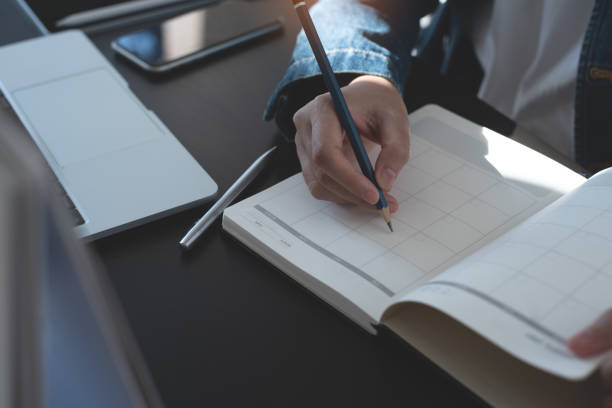 istock Event planner timetable agenda plan on year 2023 schedule event. Business woman checking timetable, taking note on calendar planner notebook on office table. Calendar event plan, work planning 1528015474