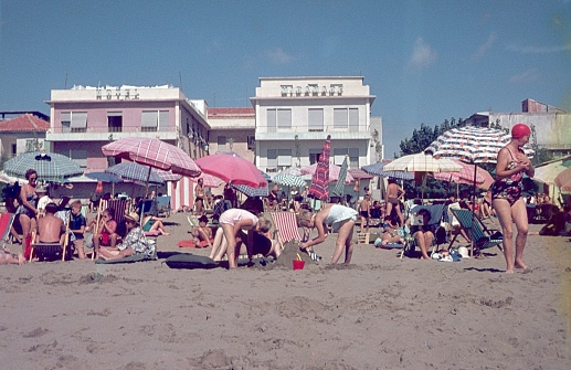 Rimini Region, Emilia Romagna, Italy, 1965. Beach scene with holidaymakers from Central Europe on the Adriatic Sea beach of in the Rimini Region. Also: hotels and beach accessories.