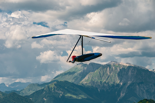 Hang glider pilot soars above Soca valley in Slovenia with Julian Alps and mount Krn on the background. Visit Slovenia. Europe popular tourist destination