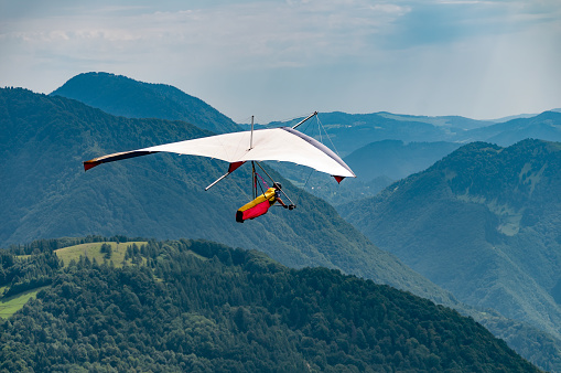 Vintage hang glider flies in the mountains in Soca valley. Extreme outdoor activities in Tolmin, Slovenia. Learning to fly