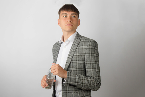 Young entrepreneur wearing a suit jacket and open neck shirt without a tie opeing a plastic bottle of water