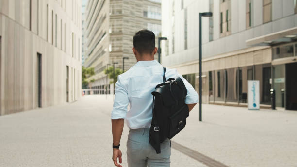istock Young businessman walking through the business district, back view 1528135141