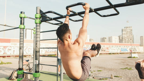 istock Guy, athlete on a horizontal bar raises his legs, hangs on a horizontal bar and does an exercise of the abdominal muscles in an outdoor sports field on a sea area on a summer day 1528137967
