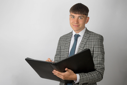 Young entrepreneur wearing a suit and tie holding a black folder and smiling